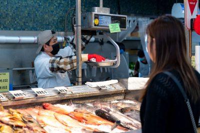 在海鲜市场为顾客称鱼的人.